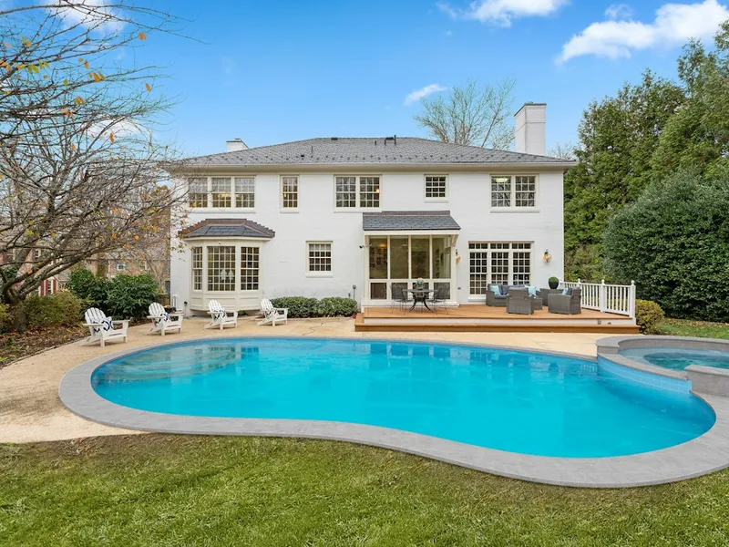 Kidney-shaped backyard pool with spa beside a two-story home in Escondido