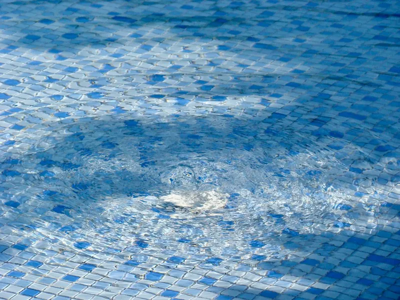 Close-up of a blue pebble and quartz pool finish under rippling water