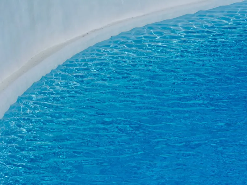 Smooth new white plaster finish along the curved wall of a resurfaced Escondido pool