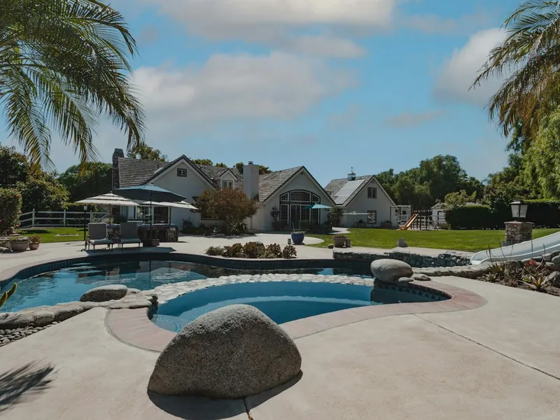 Resurfaced free-form pool and spa with boulders and palm trees in Escondido